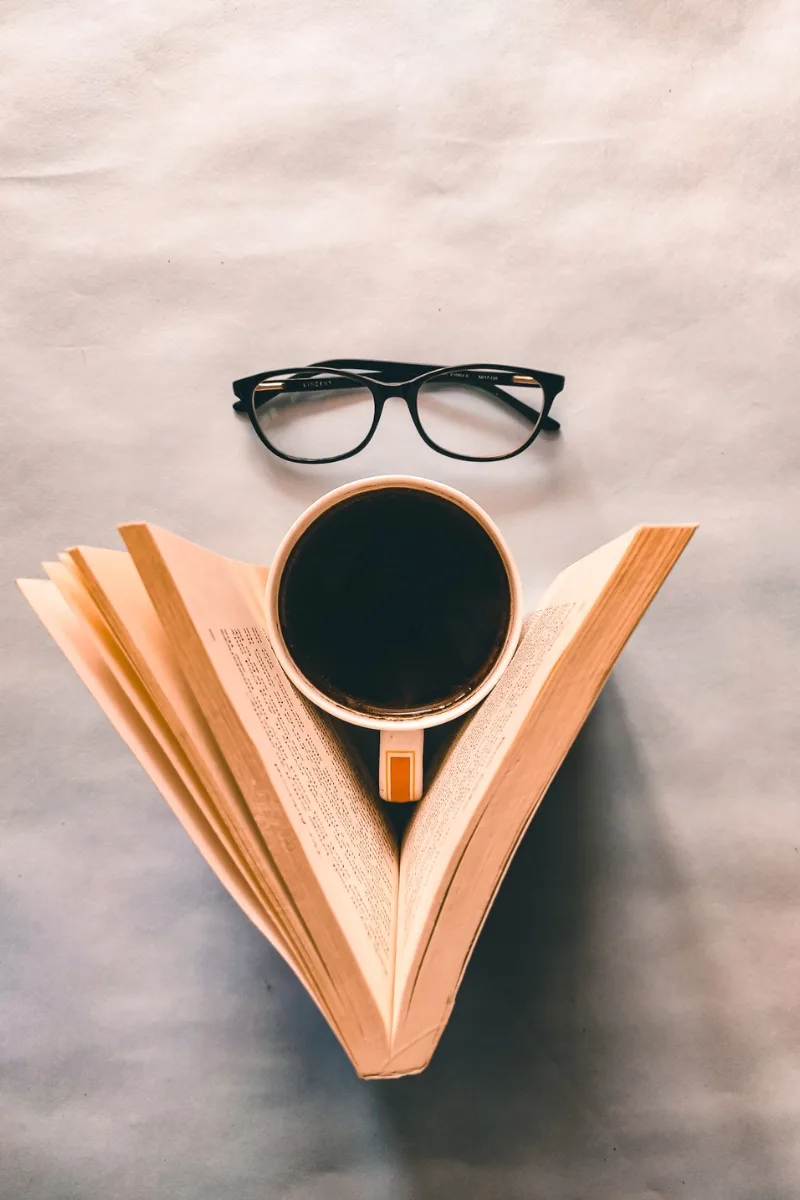 glasses, coffee mug, and an open book