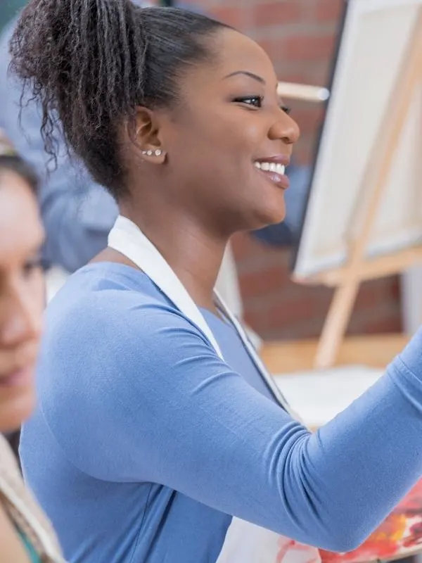 woman smiling painting a canvas