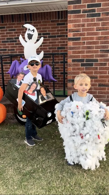 child standing in front of a Halloween inflatable dressed as a storm chaser. Another child is wearing a homemade tornado costume