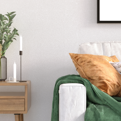 Cozy living room with layered pillows, green throw blanket, flowers, candles, and natural textures