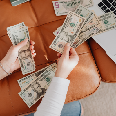 Woman counting cash next to a laptop while planning a no-spend weekend